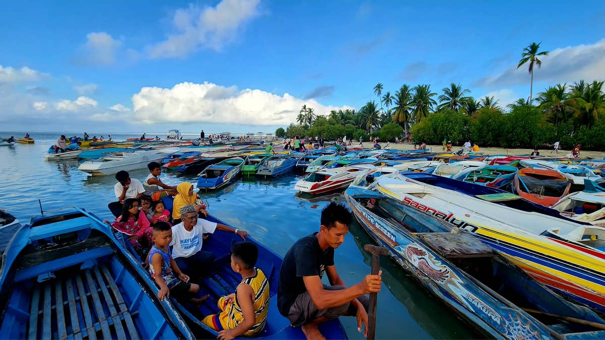 A family arrives on the shore of Bumbun Island, already filled with boats.